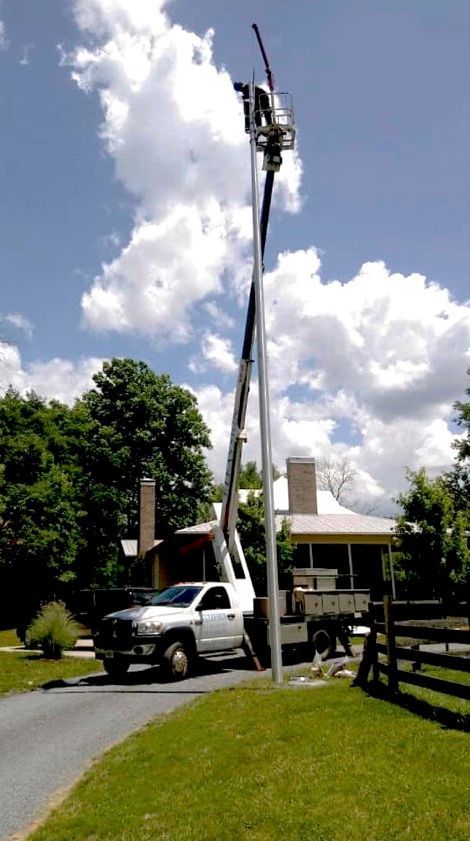 A white truck is parked on the side of the road next to a pole.