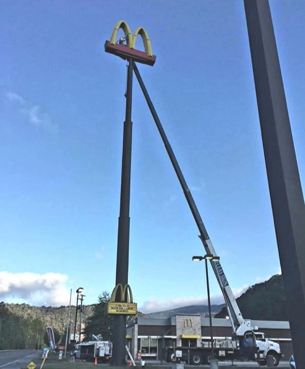 A mcdonald 's sign is being lifted by a crane