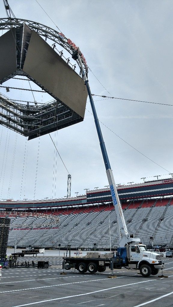 A crane is lifting a large structure in a parking lot.