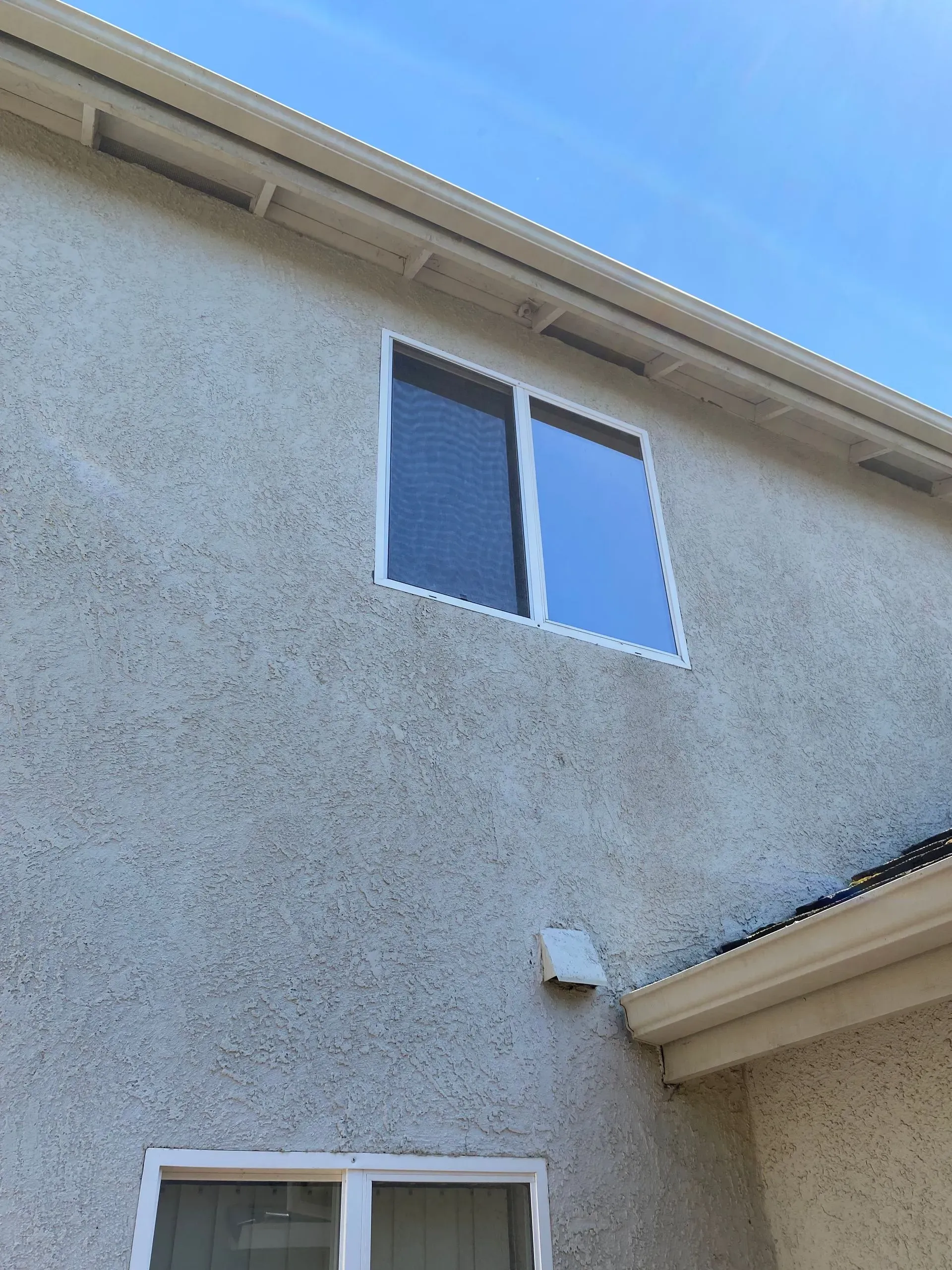 A house with two windows and a blue sky in the background