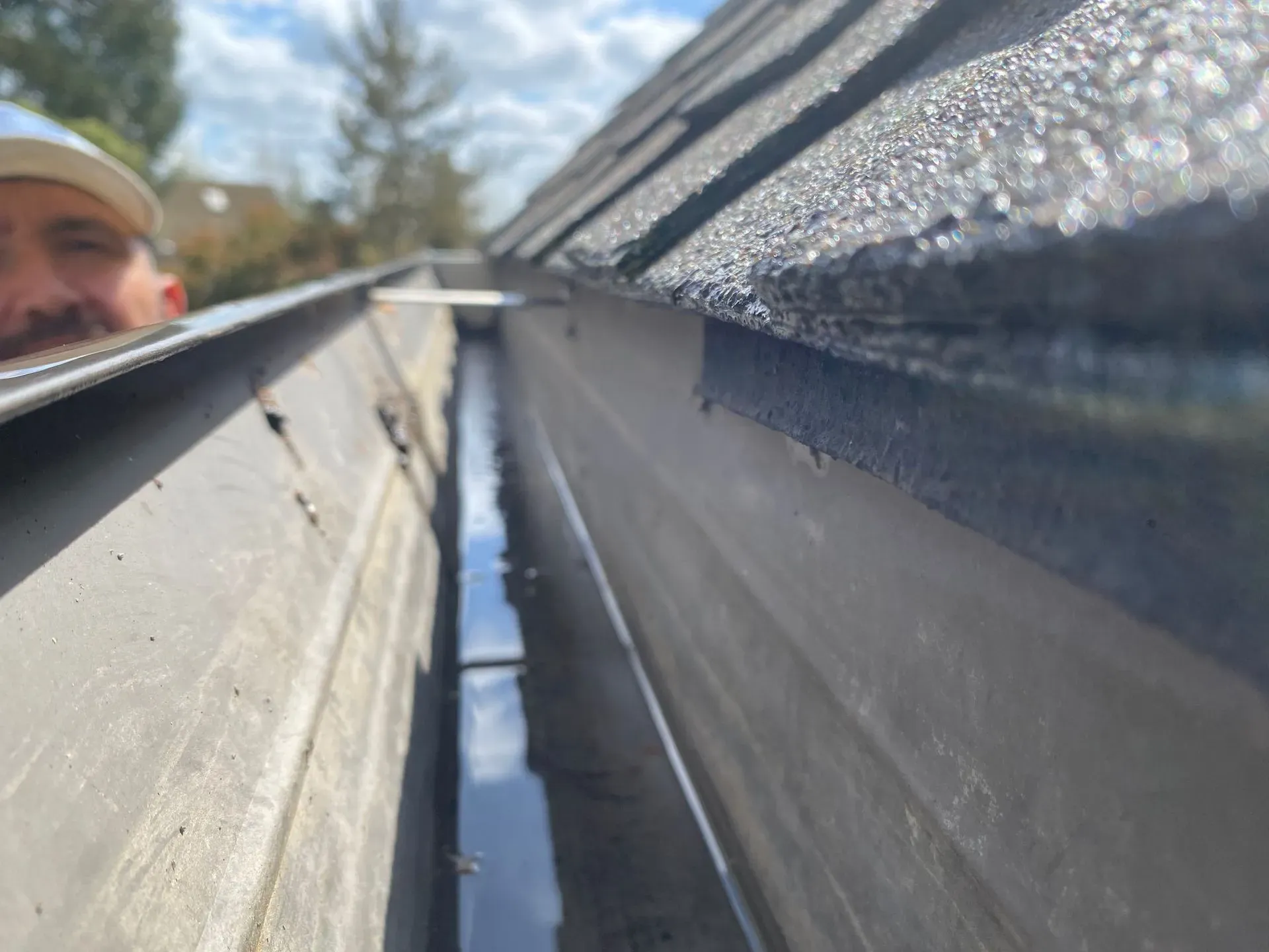 A man is looking down at a gutter on a roof.