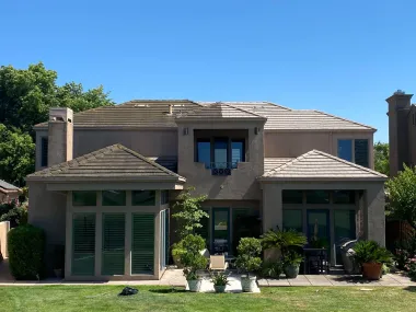 A man is standing on a ladder on the roof of a house.