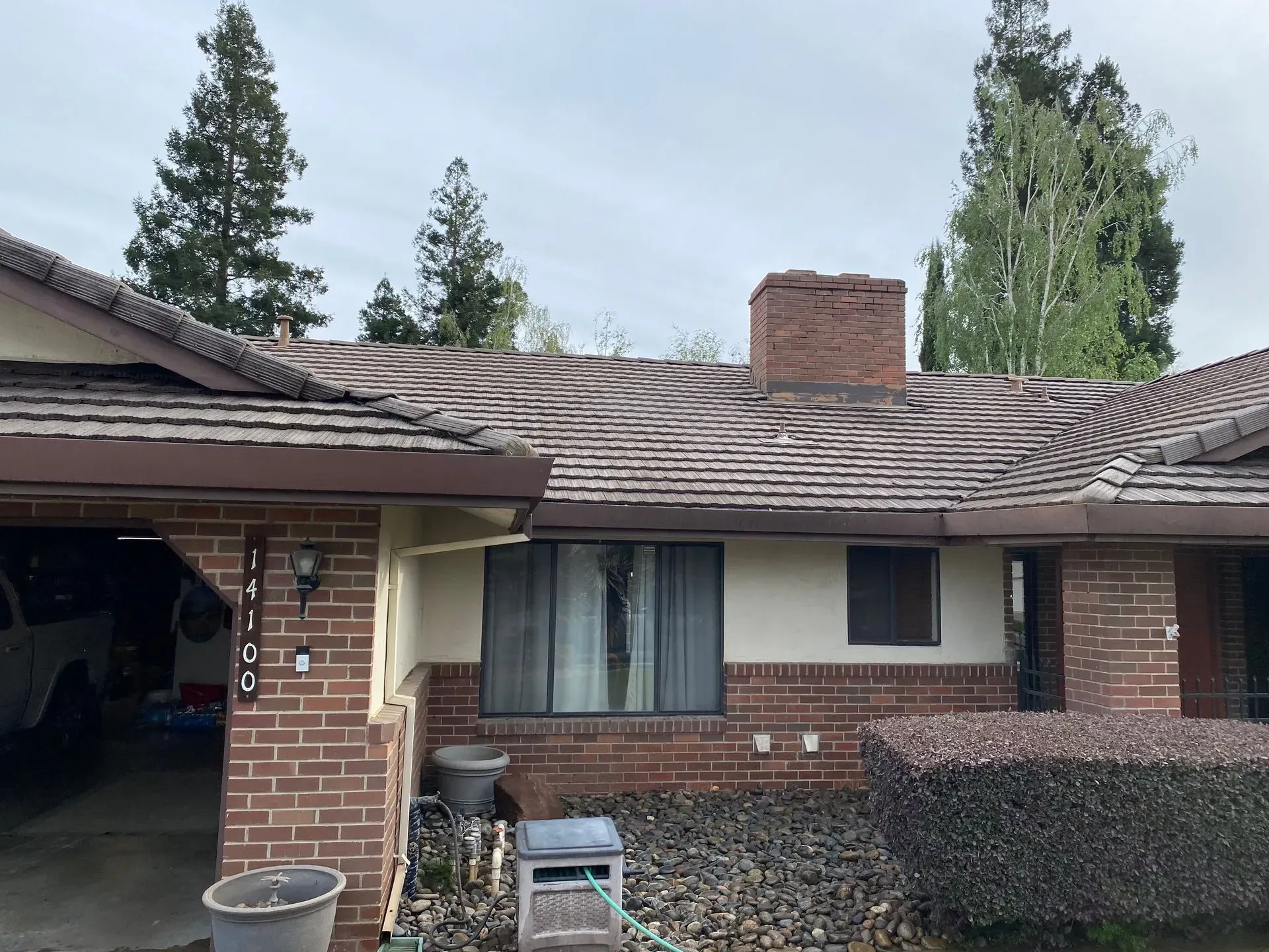 A brick house with a garage and a chimney on the roof.