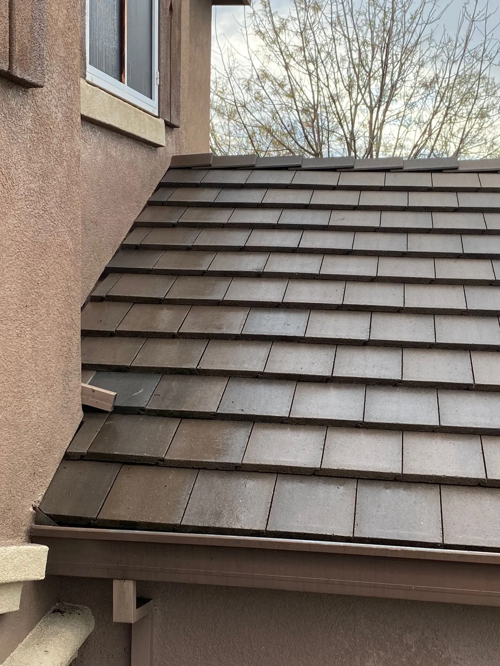 A close up of a roof with a window in the background