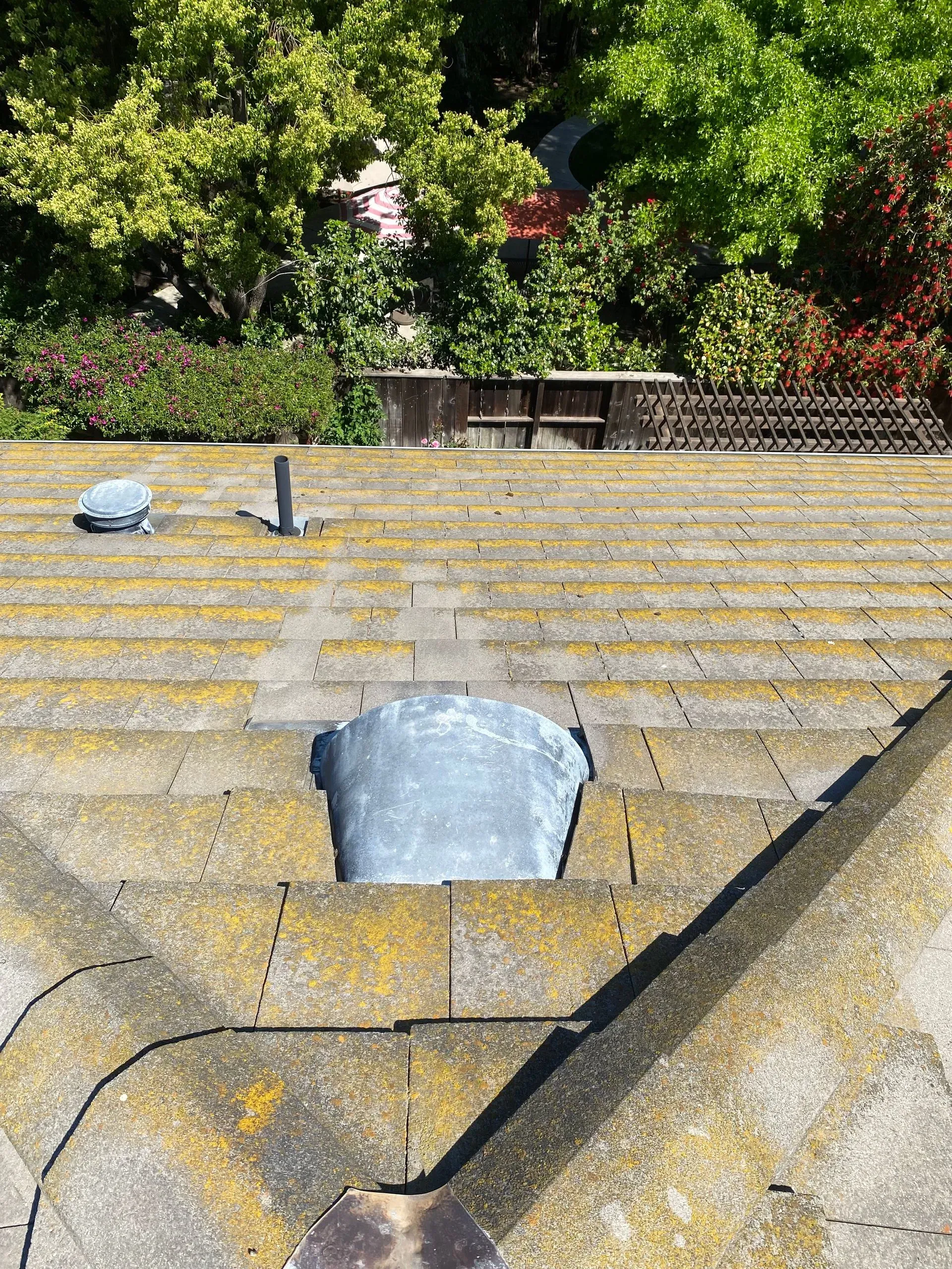 A roof with a hole in it and trees in the background.