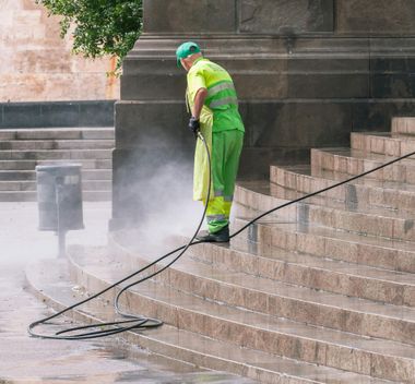 A man is cleaning the roof of a house with a high pressure washer.