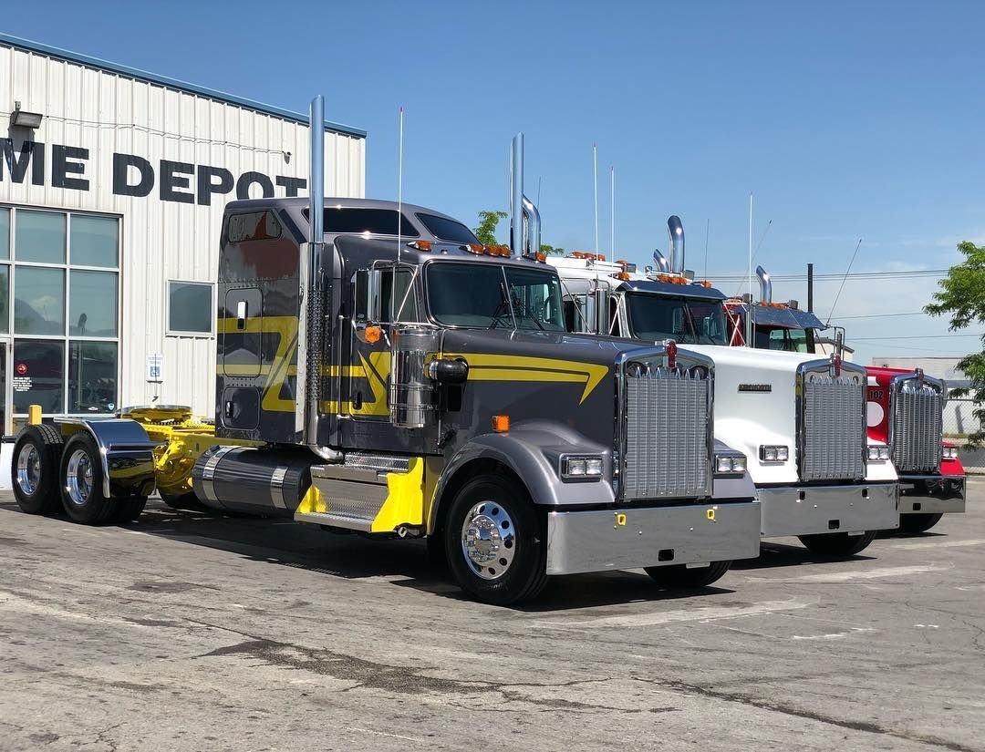 Three semi trucks are parked in front of a building.