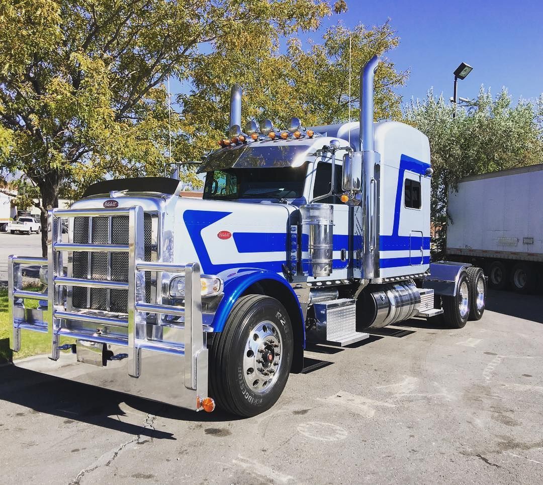 A blue and white semi truck is parked in a parking lot.