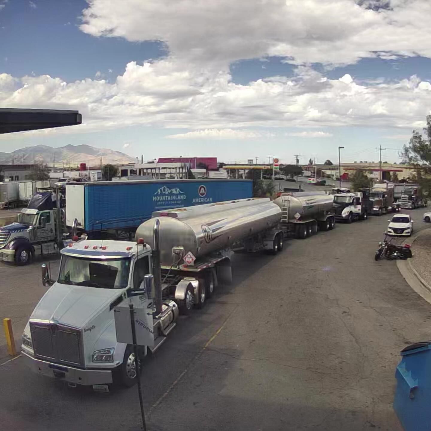 A row of tanker trucks are parked on the side of the road