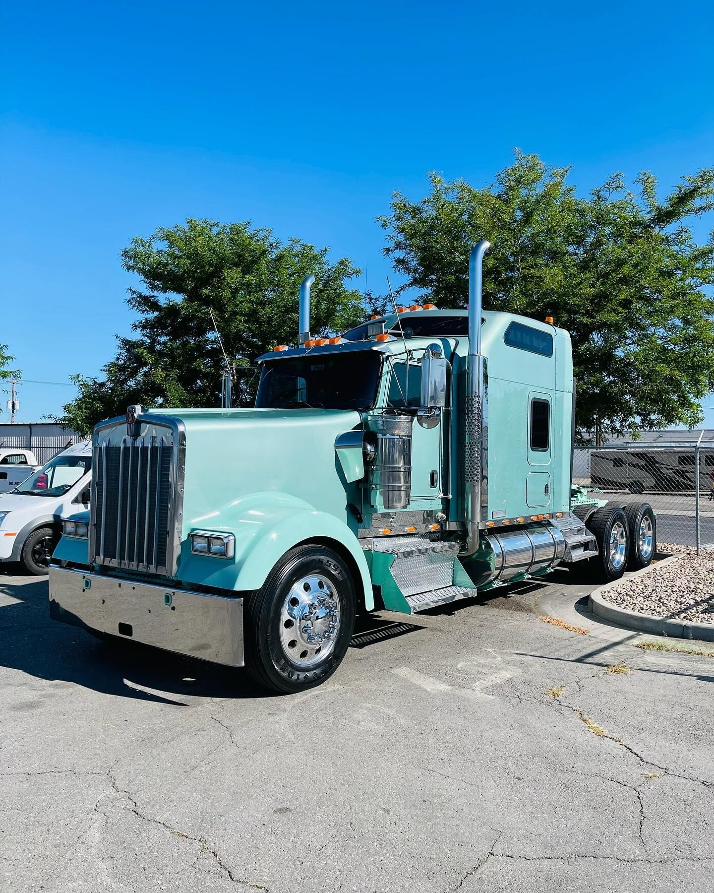A green semi truck is parked in a parking lot.