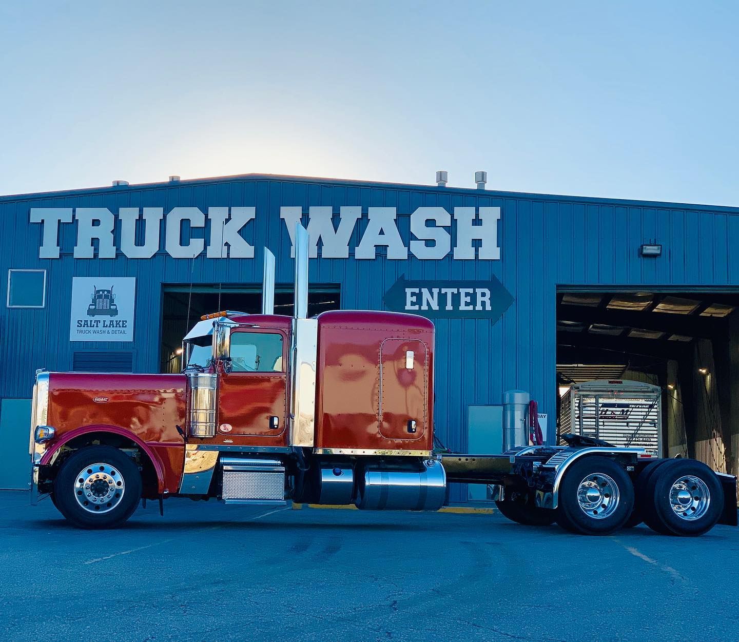 A red semi truck is parked in front of a truck wash