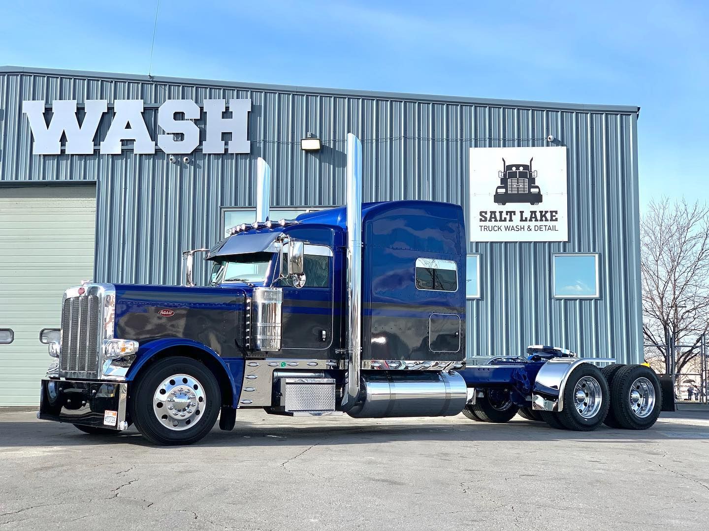 A blue semi truck is parked in front of a building.