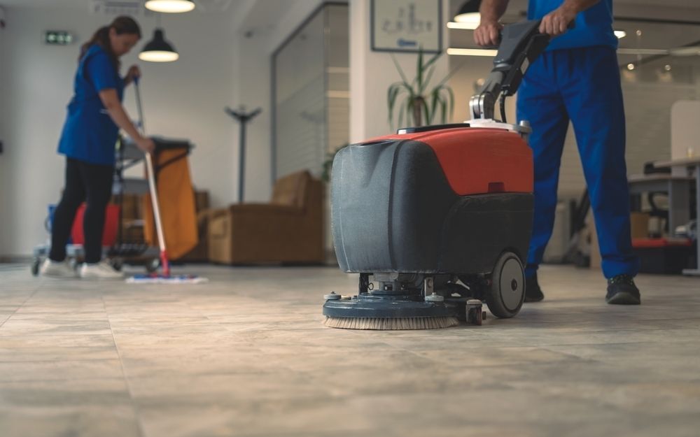 A man is using a machine to clean the floor in an office.