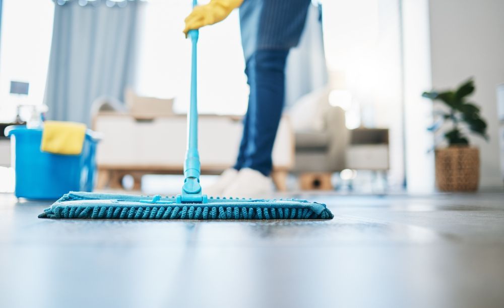 A person is cleaning the floor with a mop in a living room.