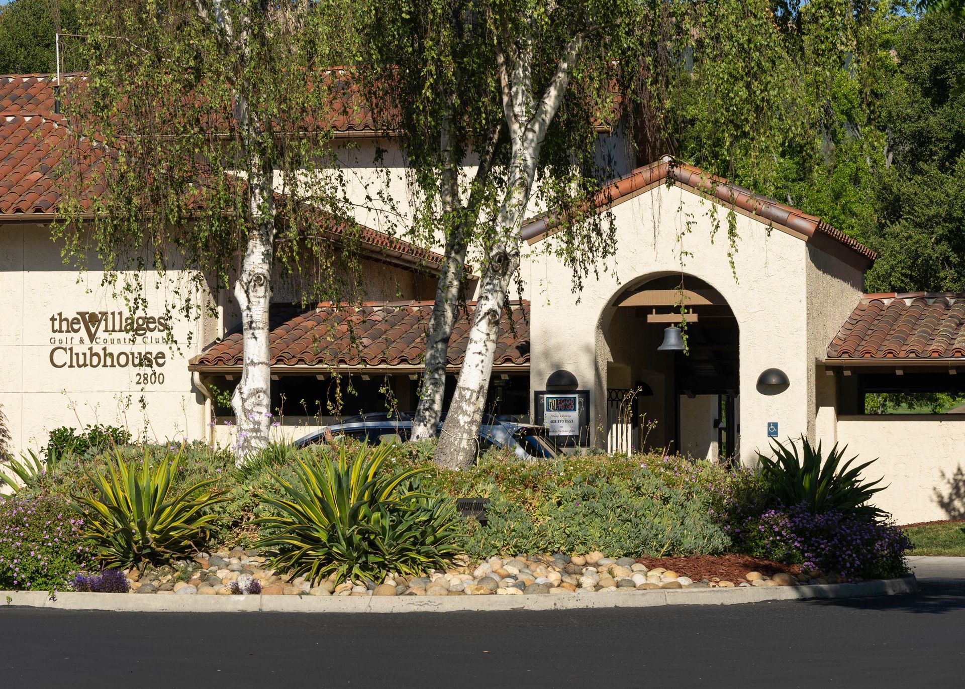 The villages golf and country club building behind trees and bushes.