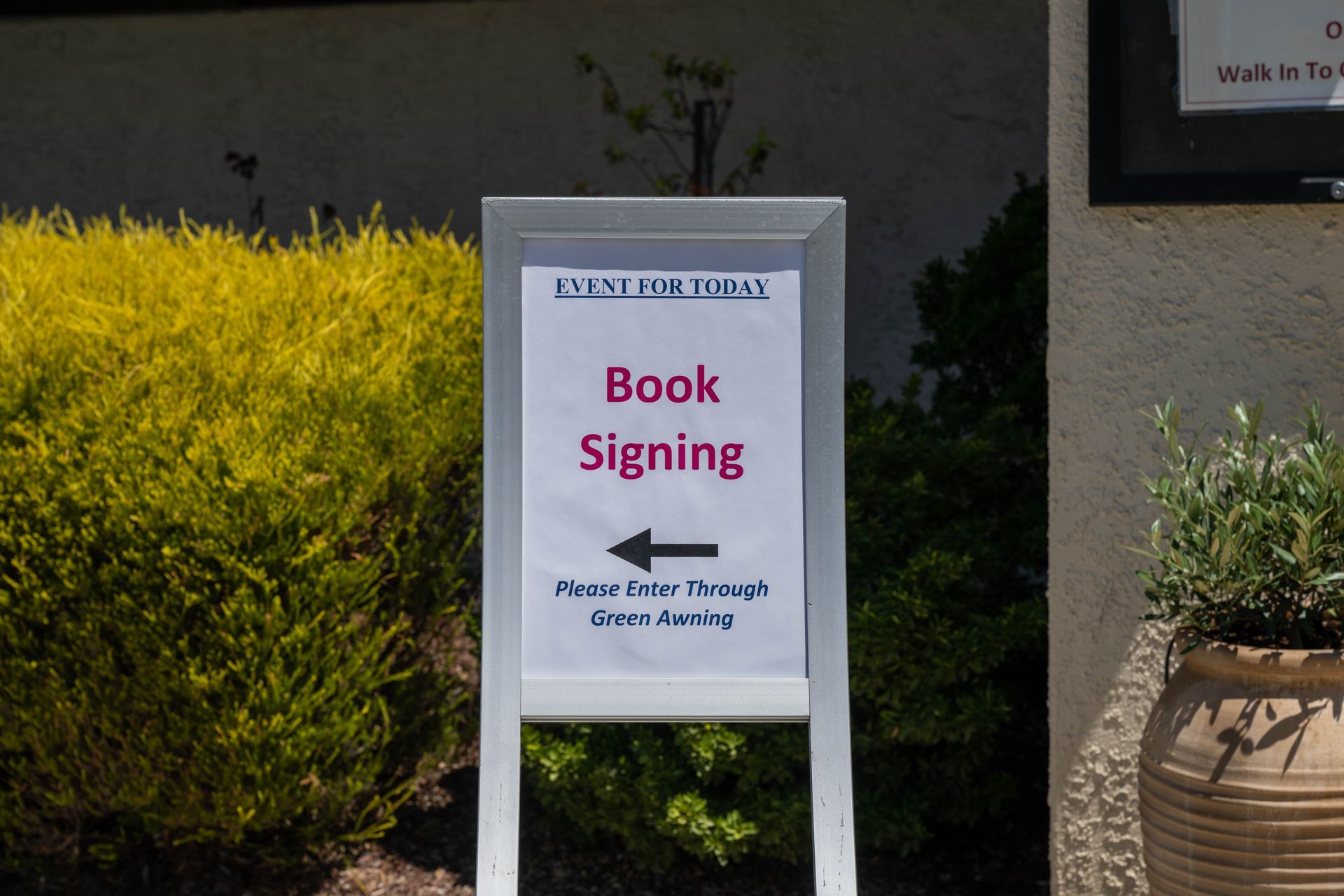 A book signing sign with an arrow pointing to the left.