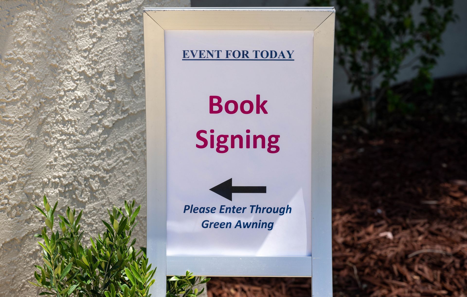 A sign that says book signing with an arrow pointing to the left.