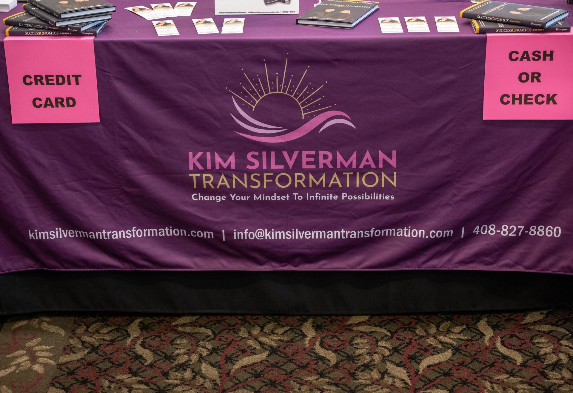 A table with a purple table cloth that says kim silverman transformation