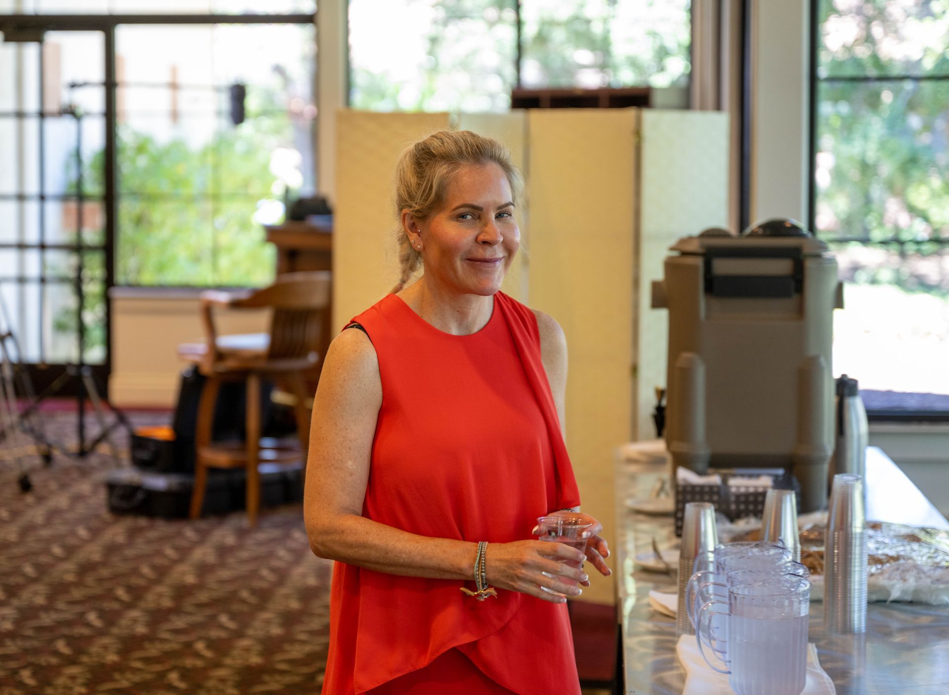 A woman in a red dress is standing in a room next to a counter.