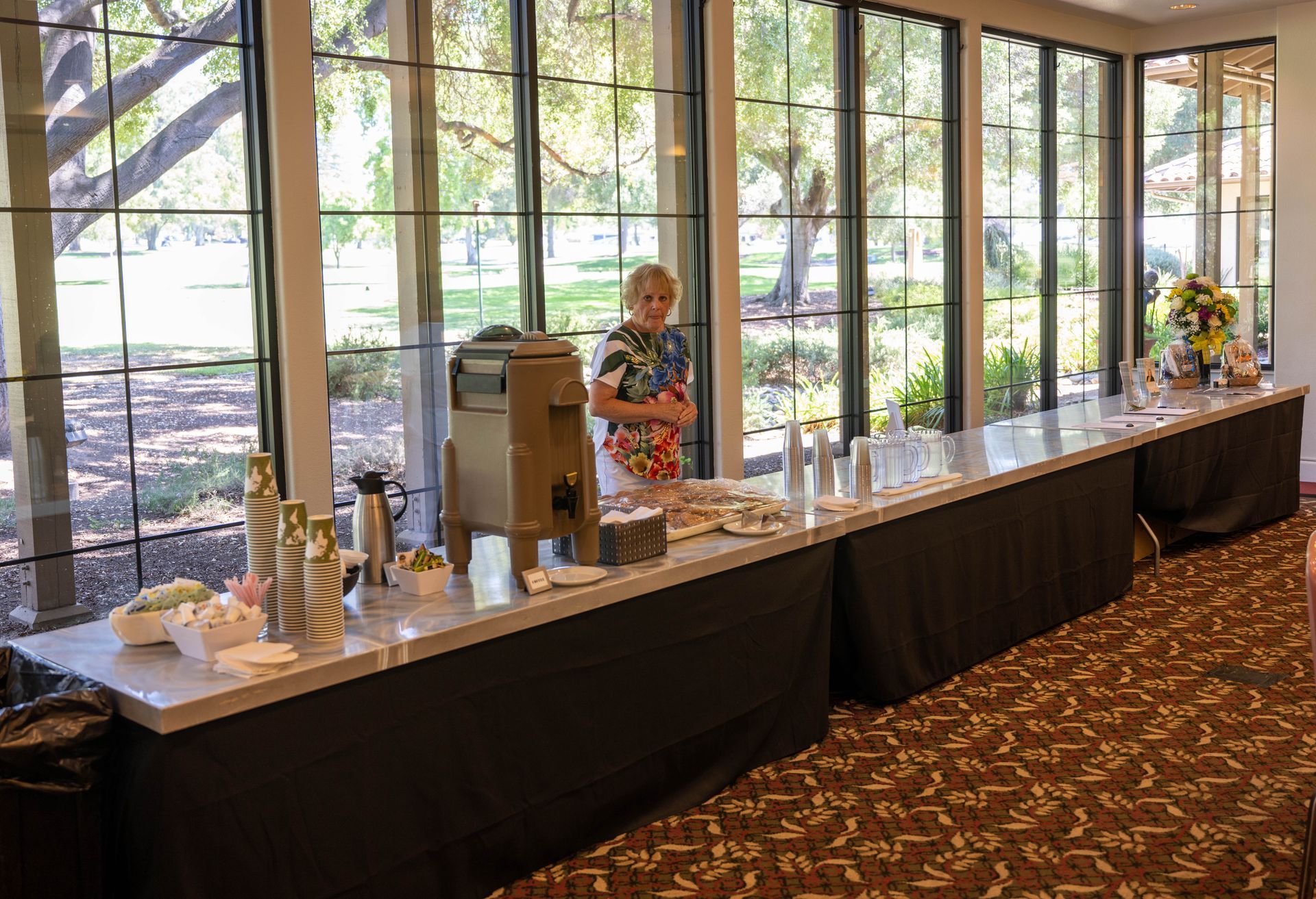 A woman is standing in front of a long buffet table.