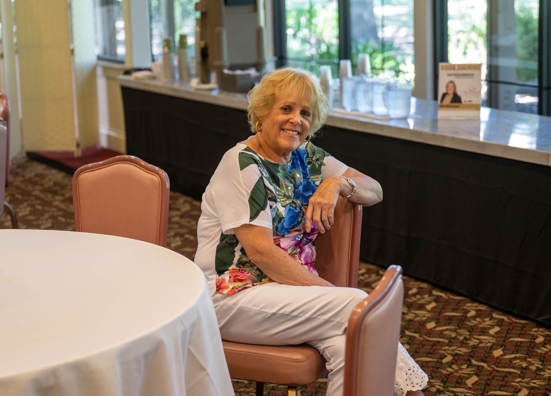 A woman is sitting in a chair in front of a table.