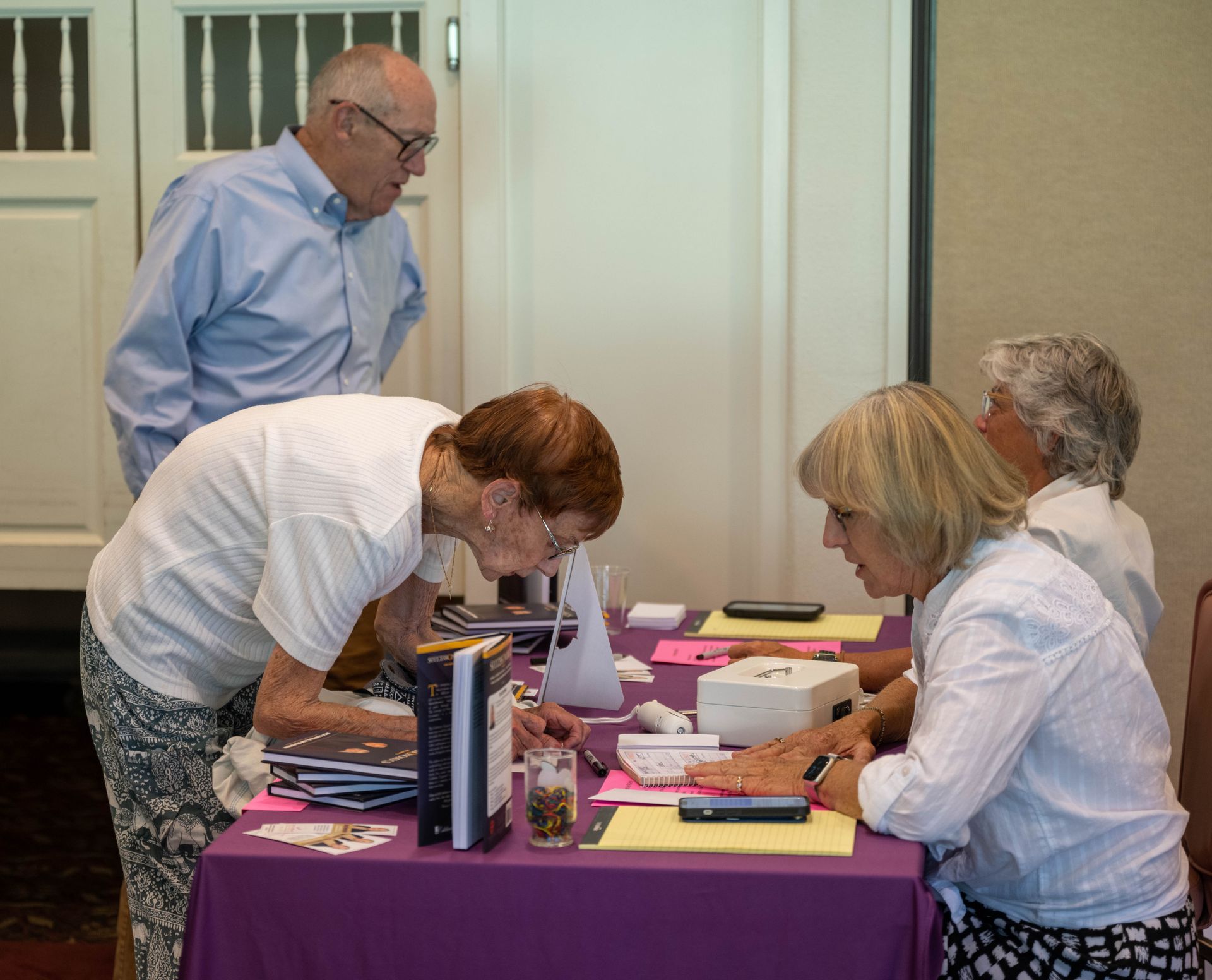 A group of people are sitting at a table signing papers.