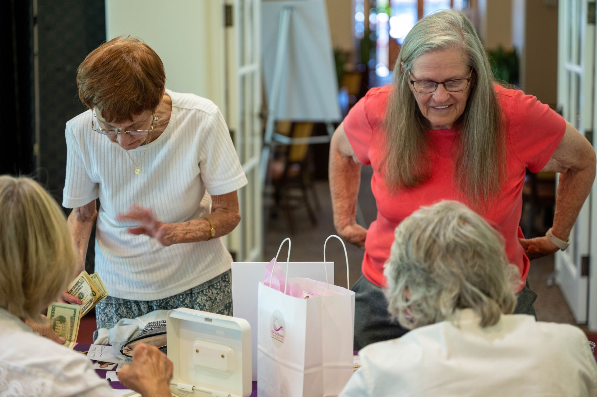 A group of older women are standing around a table looking at something.