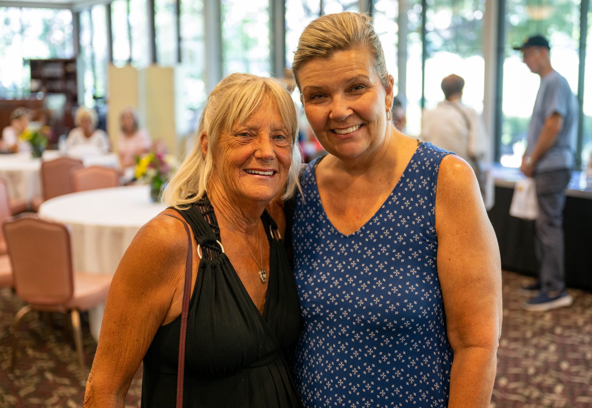 Two women are posing for a picture together in a room.