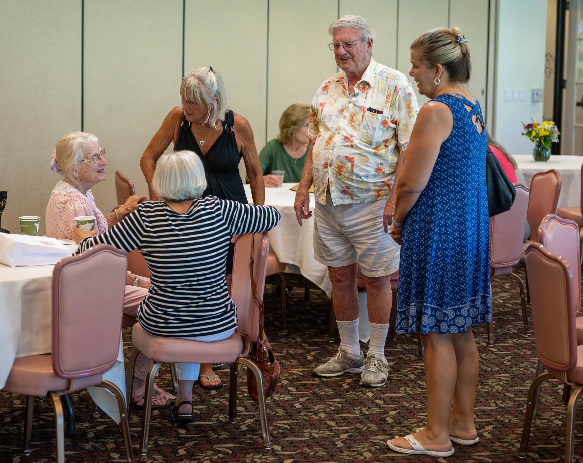 A group of people are standing around a table talking to each other.