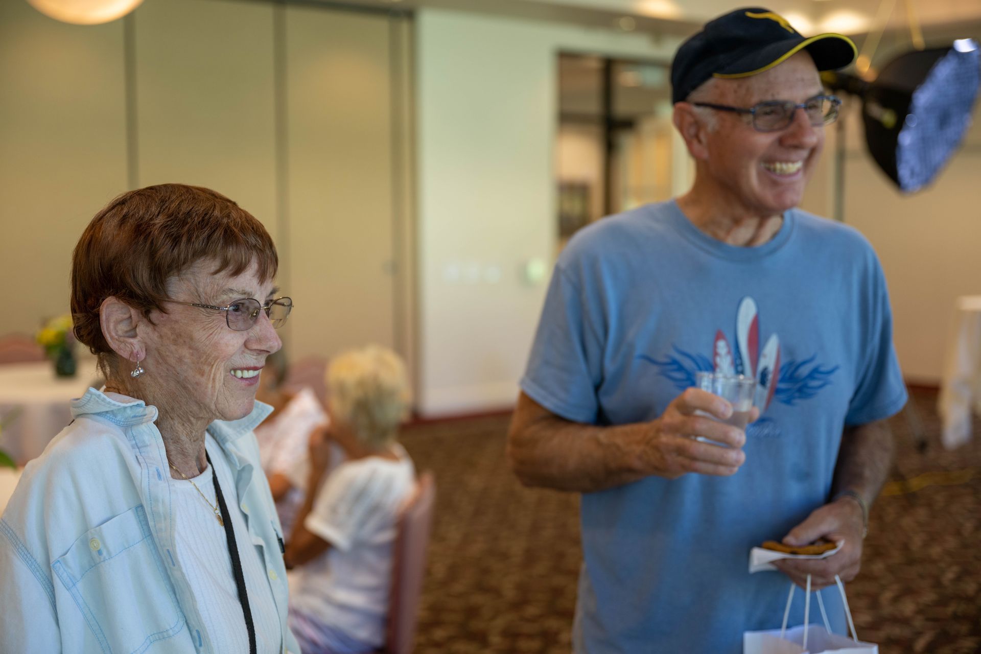 A man and a woman are standing next to each other in a room and smiling.