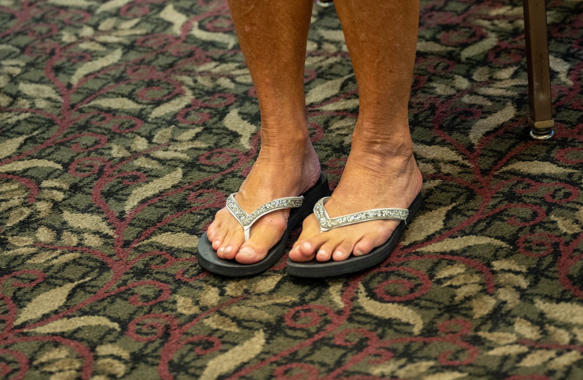 A woman is wearing a pair of flip flops on a carpet.