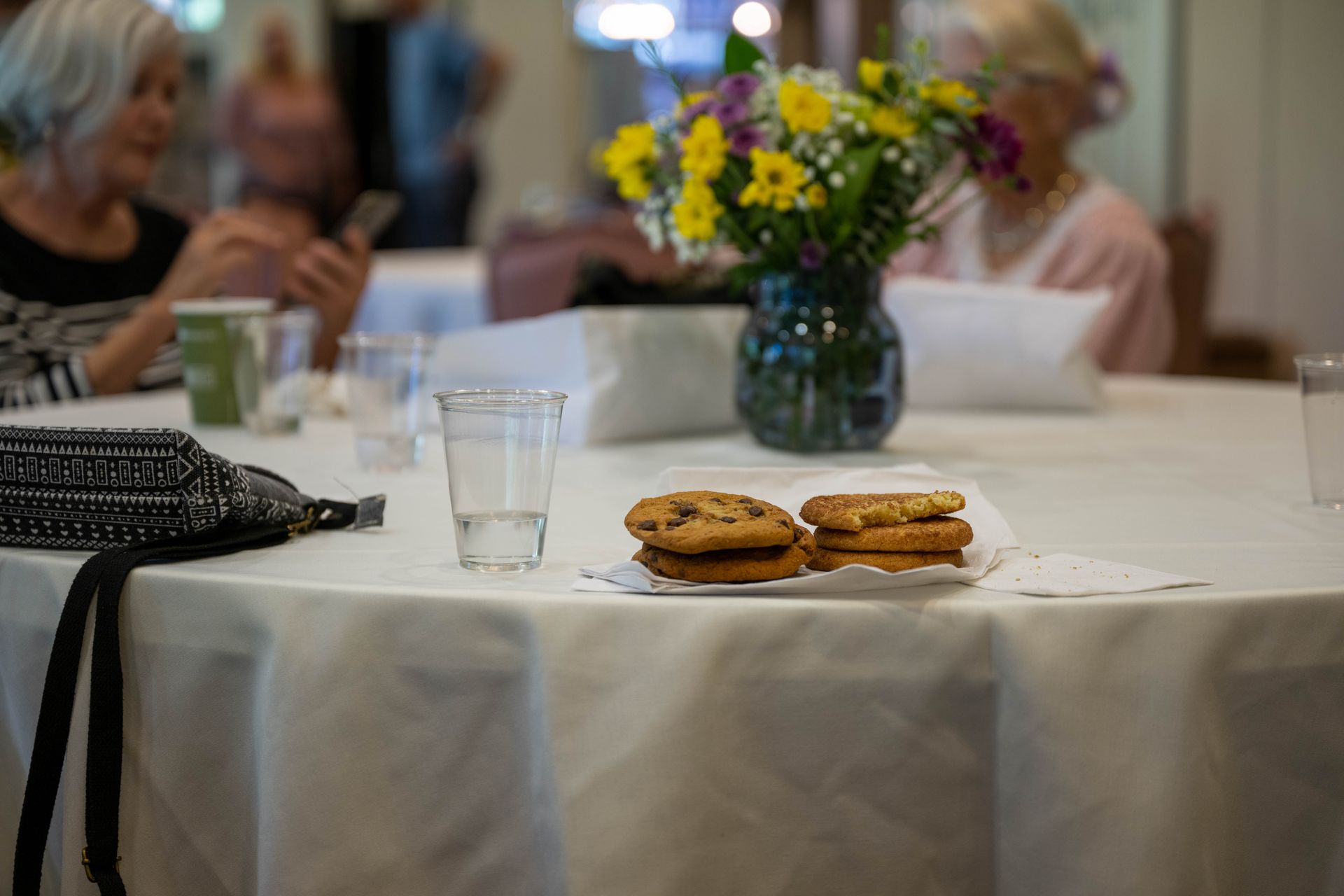 A plate of cookies and a glass of water on a table.