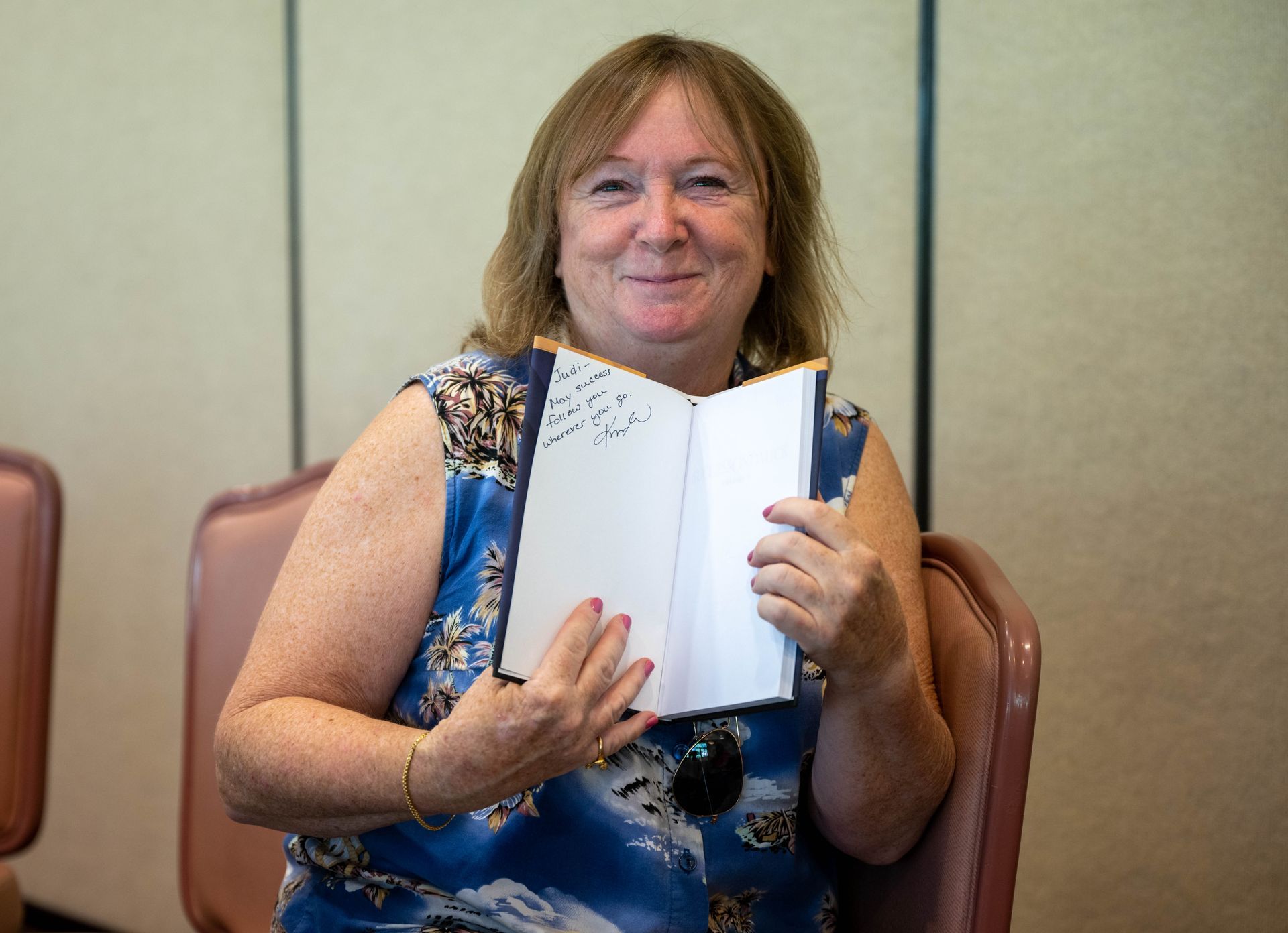 A woman is sitting in a chair holding a book in her hands.