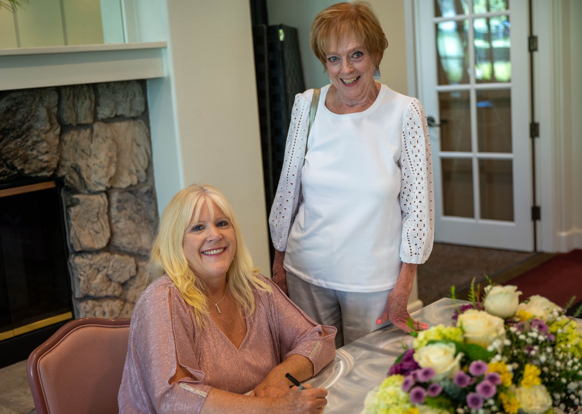 Kim Silverman and a women are next to each other at a table with flowers.