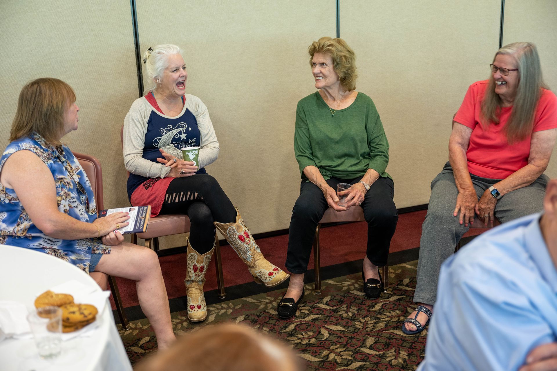 A group of women are sitting in chairs talking to each other.