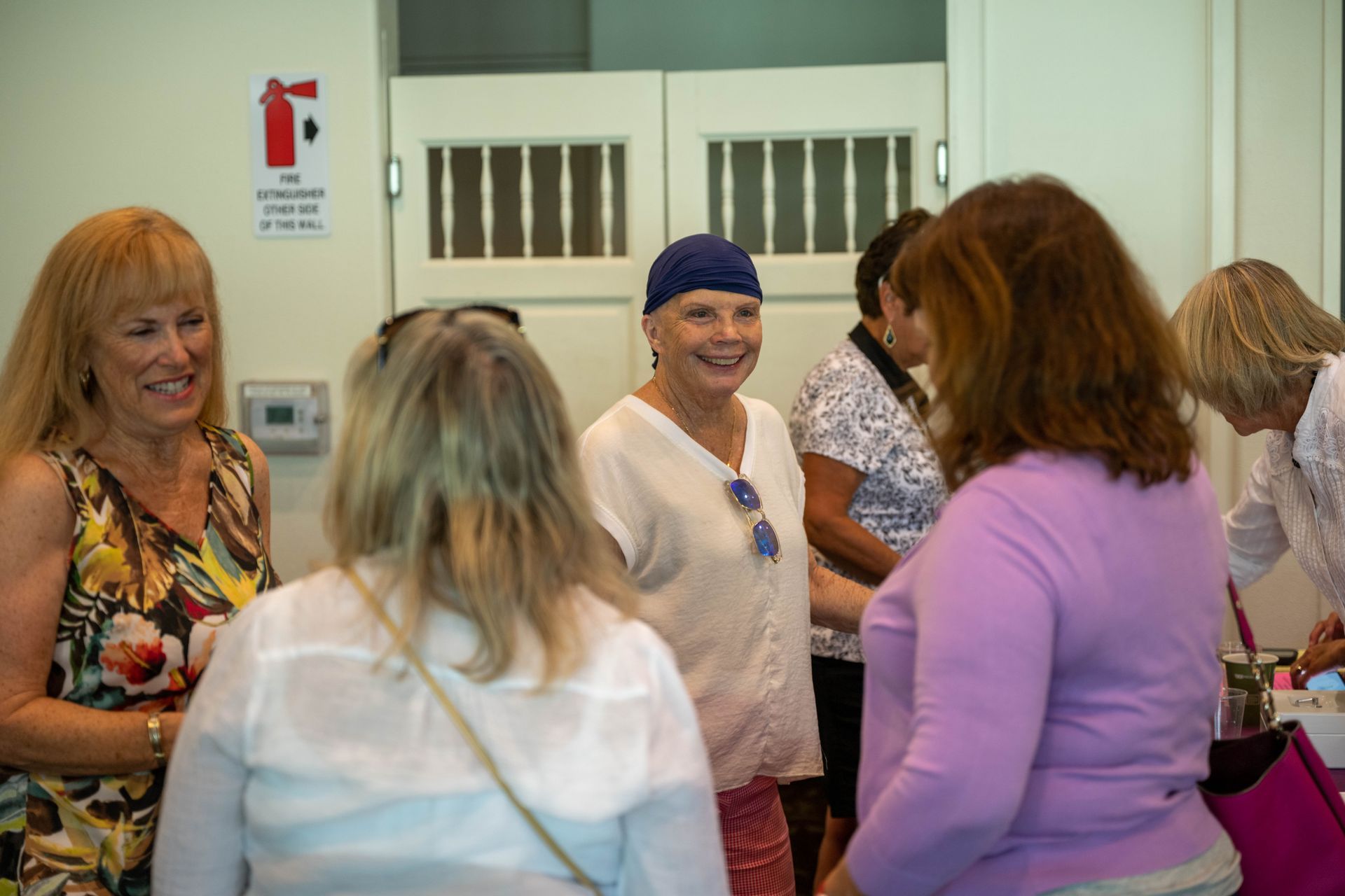 A group of women are standing in a room talking to each other.