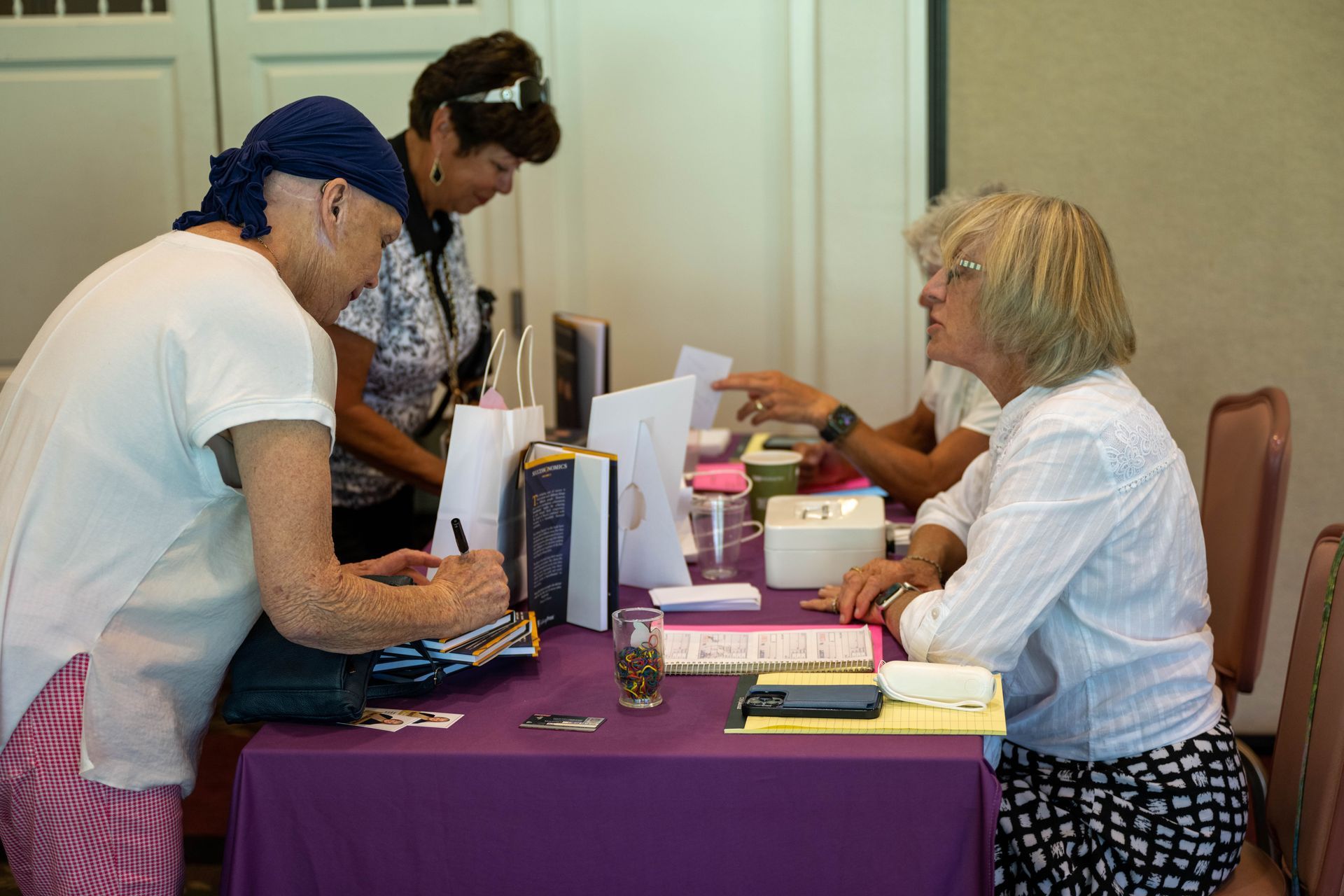 Two women are sitting at a table talking to each other.