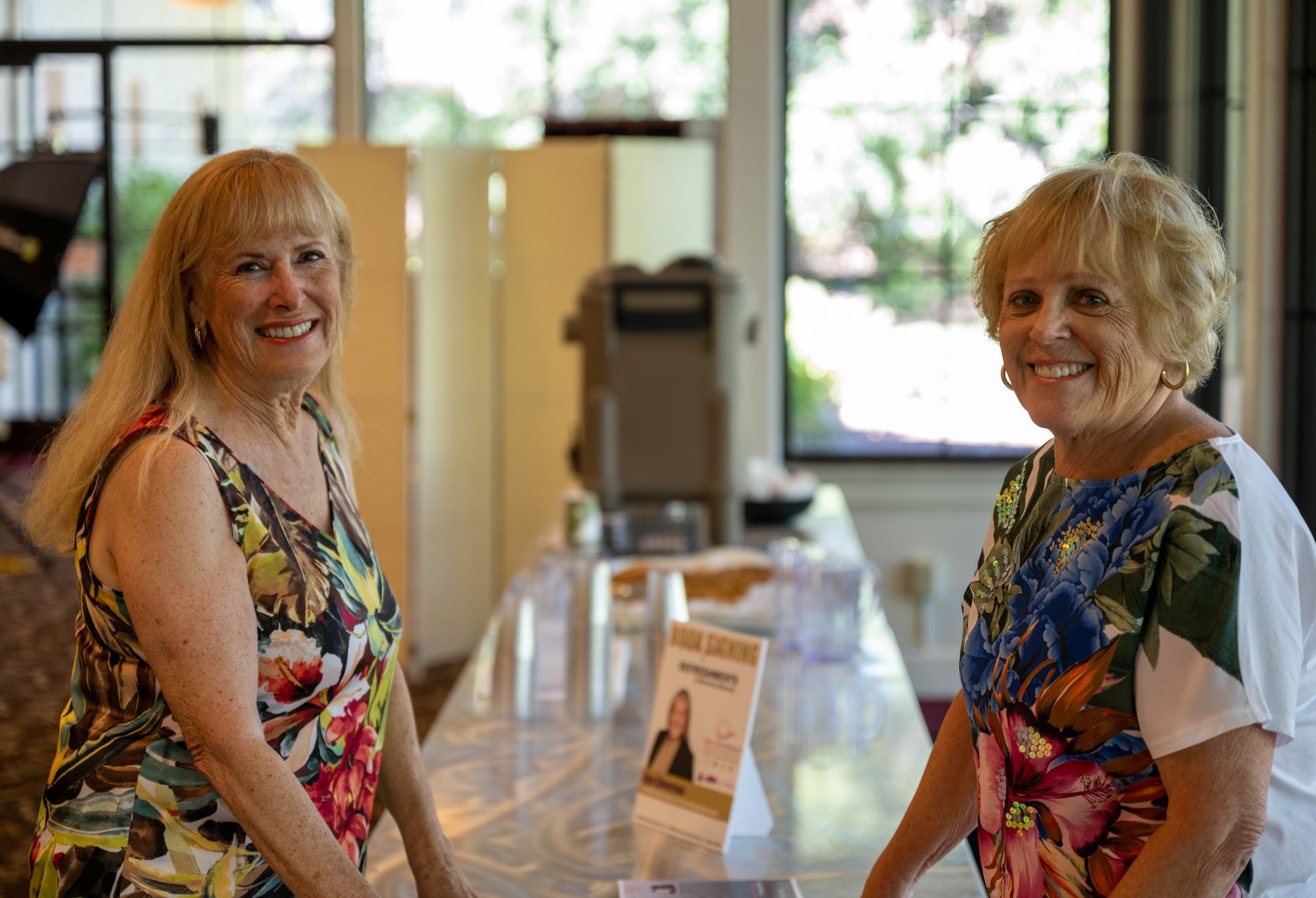 Two women are standing next to each other in front of a table.