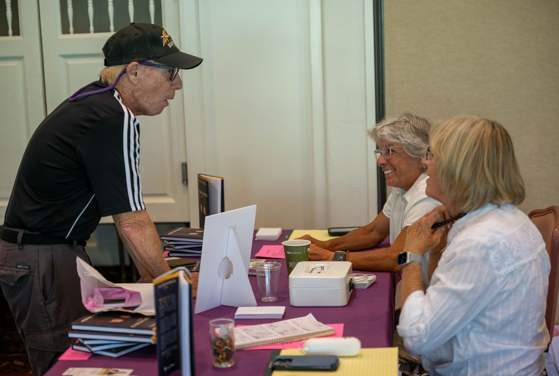 A man is talking to two women sitting at a table.