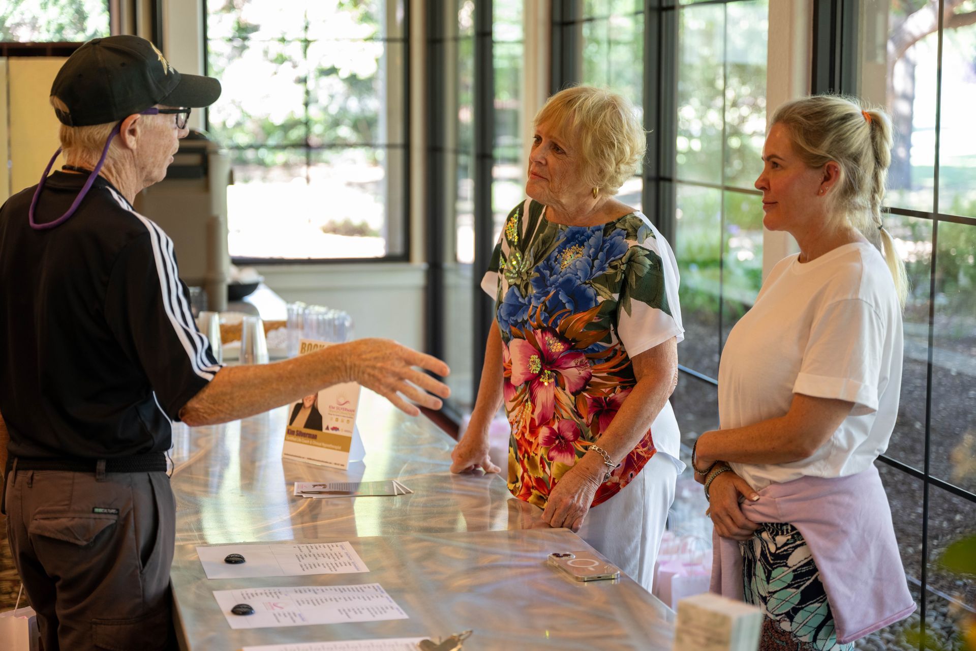 A man is talking to two women at a counter.