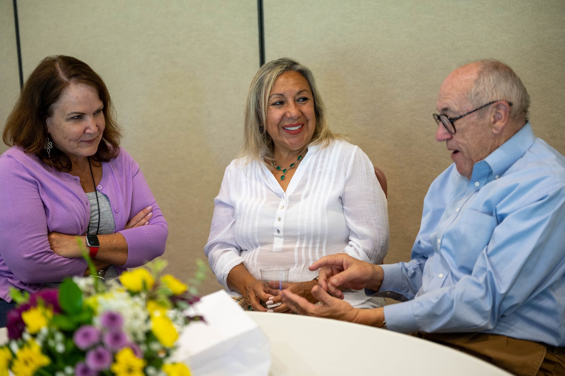 A man and two women are sitting at a table talking to each other.