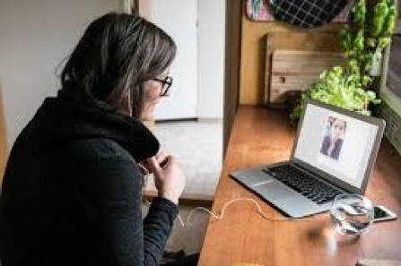 A woman is sitting at a desk in front of a laptop computer.