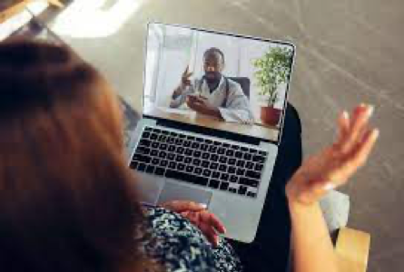 A woman is having a video call with a doctor on her laptop.