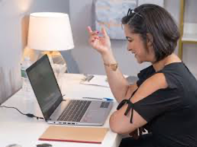 A woman is sitting at a desk using a laptop computer.