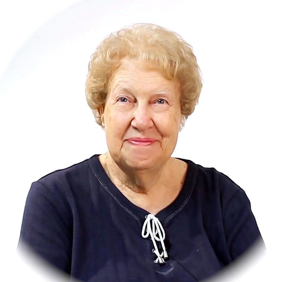 Dolores Cannon wearing a black shirt and a necklace is smiling for the camera.