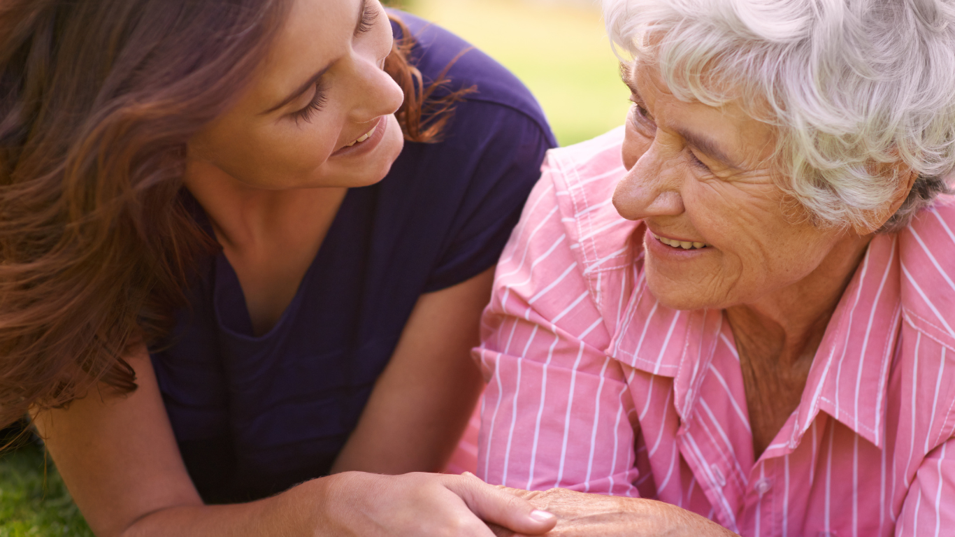 A young woman is holding the hand of an older woman.