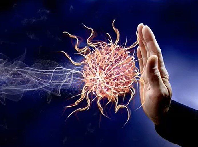 A person 's hand is blocking a virus from reaching out towards them.