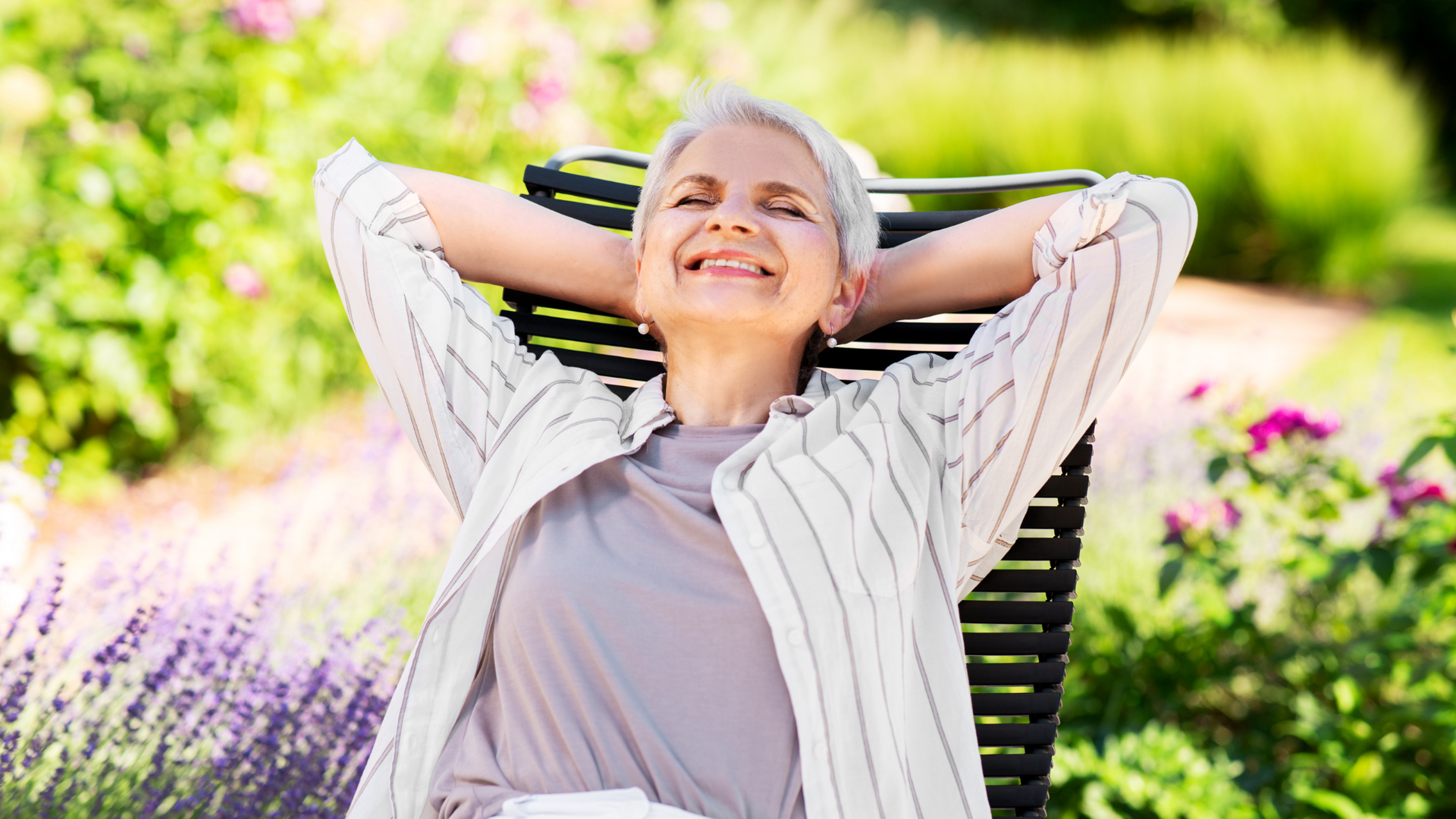 A woman is sitting in a chair with her hands behind her head.