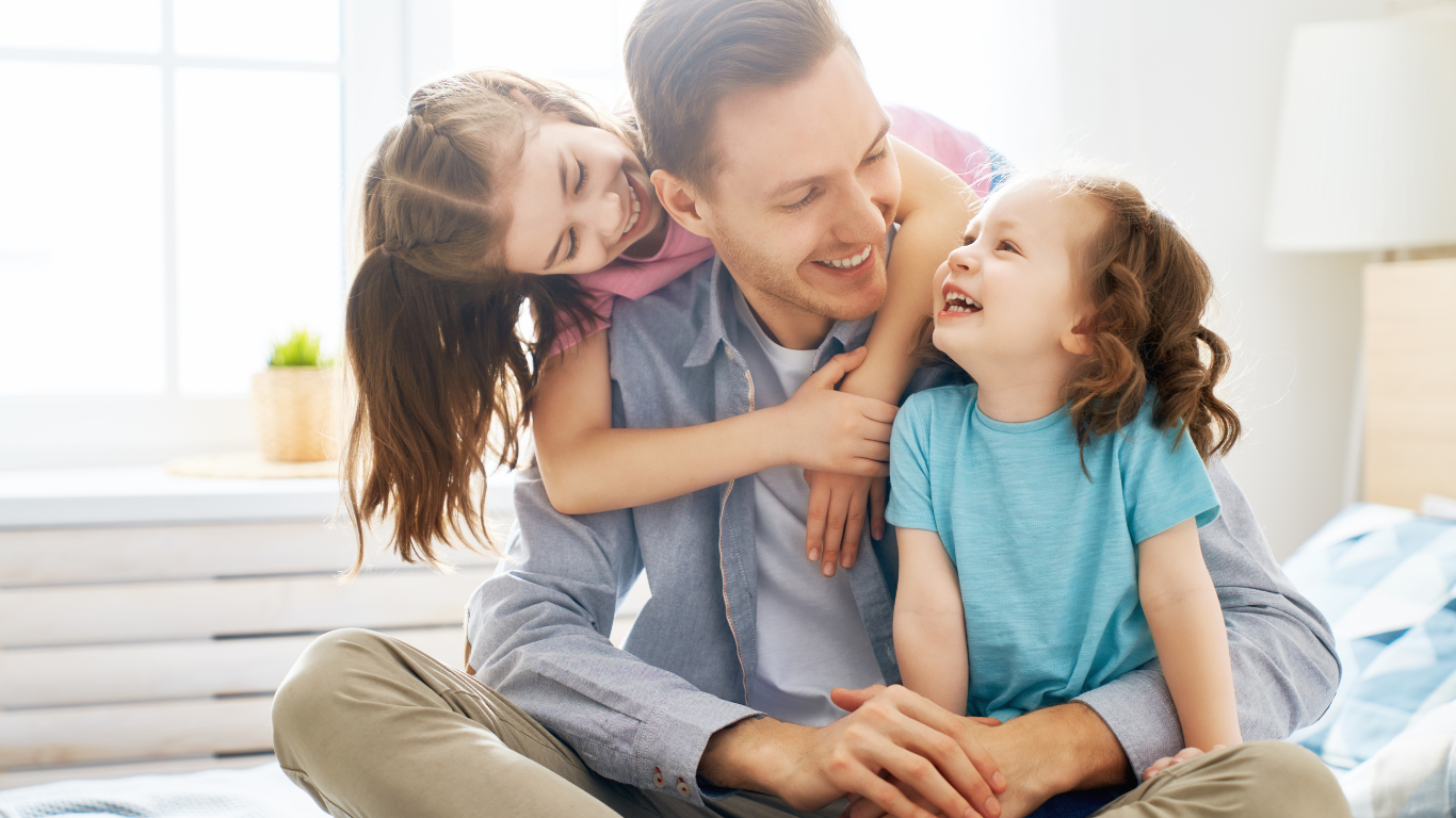 A man is sitting on the floor with two little girls.