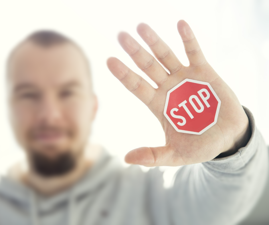 A man holds up his hand with a stop sign on it